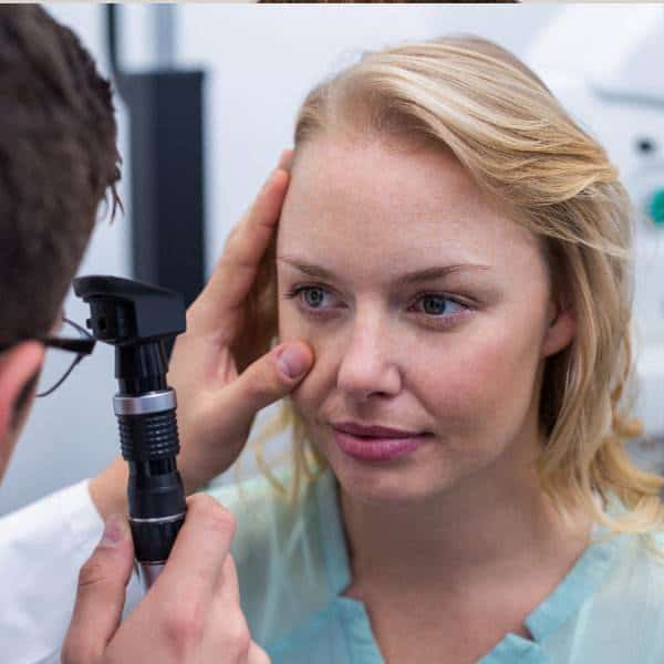 A woman is having her eyes examined by an optometrist.