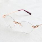 A pair of gold rimmed glasses on a white surface.